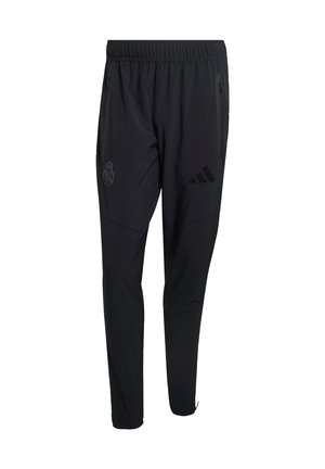 Juodos sportinės kelnės su elastinga liemeniu, užtrauktukais kišenėse, „Adidas“ logotipu dešinėje šlaunyje ir „Real Madrid“ herbu kairėje šlaunyje.