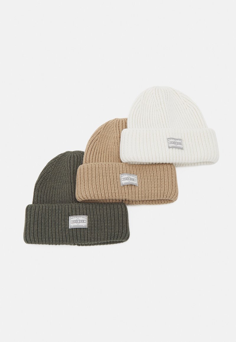 Tre strikkede beanies i olivengrøn, tan og hvid. Hver af dem har en tykk ribbet tekstur og en foldet manchet med et lille label.