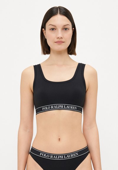 Bralette deportiva negra con escote cuadrado y tirantes anchos. Presenta una banda elástica con la marca "POLO RALPH LAUREN" en texto blanco.