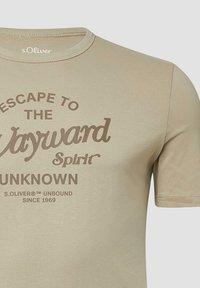 Beige kortekorte T-shirt gemaakt van katoen. Heeft een ronde hals en bedrukt tekst in bruin: "Escap naar de Wegward Spirit Onbekend".