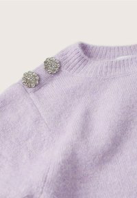 Pull en maille lavande avec deux ornements floraux en cristal sur l'épaule, tissu texturé et encolure côtelée.