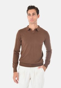 Maglione marrone a girocollo con colletto polo, maniche lunghe e orlo a costine. Realizzato in un tessuto a maglia liscia con una silhouette aderente.