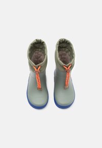 Botas verdes impermeables con un interior texturizado forrado de pelo, que presentan un cordón naranja y suelas de goma azules.
