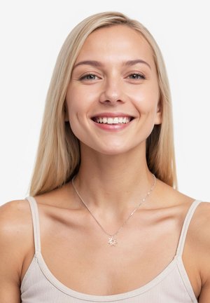 Silberne Halskette mit einem sonnenförmigen Anhänger, die an einem nackten Hals getragen wird. Das Modell hat lange blonde Haare und trägt ein beiges Tanktop.
