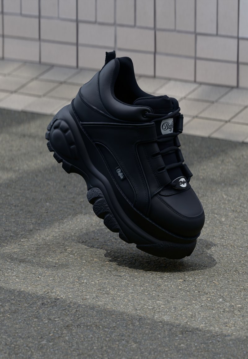 Adidași negri, cu un design masiv, din piele netedă, cu șireturi, talpă amortizată și logo embosat pe lateral. Tălpicul texturat este vizibil.