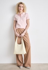 Lyserosa polo-skjorte med krage og knapper, sammen med beige vide bukser og en kremfarget, strukturert håndveske. Flate grå sko.