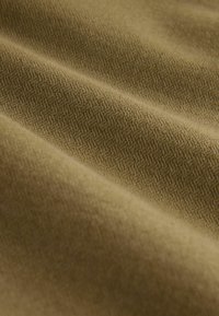 Textured, woven fabric in olive green with a subtle herringbone pattern, showcasing soft, smooth qualities and a medium thickness.