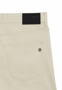 Beige denim pants with a black leather waistband. Features a back pocket with a metal logo accent. Smooth texture and tailored design.