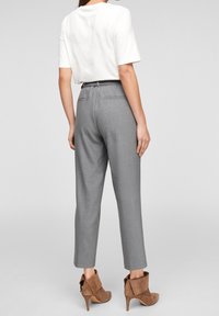 Grijze op maat gemaakte broek met een rechte snit, gecombineerd met een witte shirt met korte mouwen. Bruine enkelaars met een kleine hak.