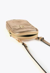 Piccola borsa a tracolla metallica dorata con texture trapuntata, cerniera dorata parzialmente aperta e sottile tracolla coordinata su sfondo bianco.