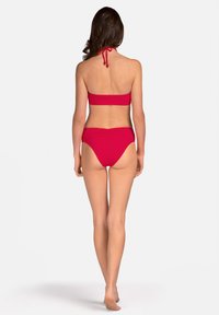 Czerwony zestaw bikini z halterem i wysokim stanem. Gładki, elastyczny materiał z minimalistycznym wzornictwem i bez wzorów.