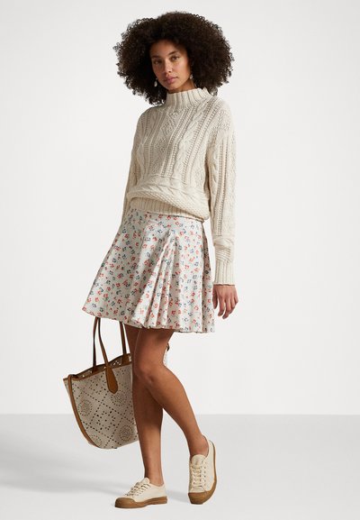 Pleteni krema pulover z kabelskimi vzorci, cvetlična plisirana krila v beli in pastelnih barvah, peščena torba, lahki športni copati z teksturiranimi podplati.