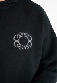 Maglione nero a maglia con un piccolo motivo a catena circolare grigio chiaro nella zona del petto.