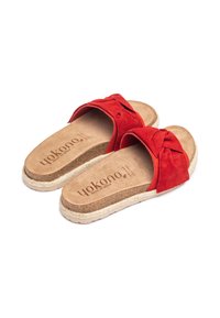 Infradito in suede rosso con dettaglio a fiocco annodato, soletta in sughero naturale e suola in juta intrecciata. Nome del marchio visibile sulla soletta.