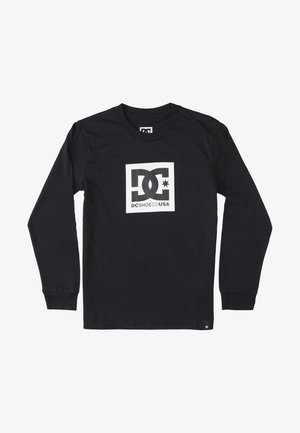 Sort langærmet skjorte med hvidt firkantet logo med stiliserede "DC" bogstaver og teksten "DCSHOECOUSA" på brystet.