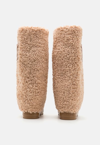 Beige nahkaherranjalkineet, joissa on teksturoitu pinta, pyöreä varvas ja tasainen kumipohja. Kantapäässä lukee "CASADEI."