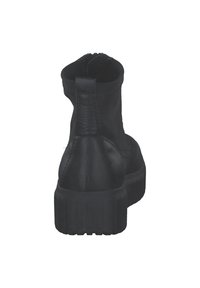 Schwarze Knöchelboots mit dicker Sohle, strukturiertem Lederabsatz und elastischem Stoff-Obermaterial, von hinten gegen einen weißen Hintergrund betrachtet.