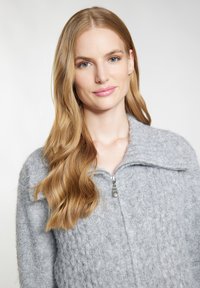 Pulover gri cu fermoar dispune de un design tricotat texturat, guler ribat și fermoar metalic. Are un aspect moale și confortabil, cu o croială lejeră.