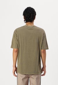 Oliven grøn bomulds t-shirt med rund halsudskæring, korte ærmer og en afslappet pasform; har en let slidtegn i teksturen.