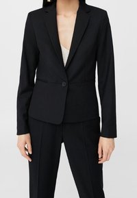 Blazer noir ajusté avec revers, fermeture à un bouton et texture de tissu lisse, associé à un pantalon assorti.