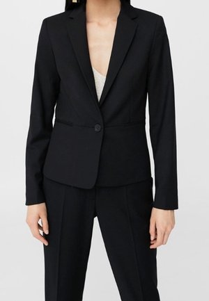 Blazer noir ajusté avec revers, fermeture à un bouton et texture de tissu lisse, associé à un pantalon assorti.