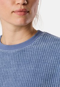 Maglione a costine blu chiaro con una superficie testurizzata e un collo rotondo. Presenta un colletto a contrasto di una tonalità blu più scura.