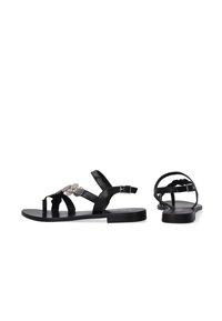 Zwarte leren sandalen met een platte zool, decoratieve zilveren hardware en verstelbare enkelriemen. Eenvoudig, gestrikt ontwerp met een gladde afwerking.