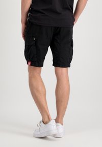 Pantalones cortos de carga negros, hechos de una tela ligera, que cuentan con múltiples bolsillos, dobladillos rematados y un pequeño parche rojo en la parte trasera.