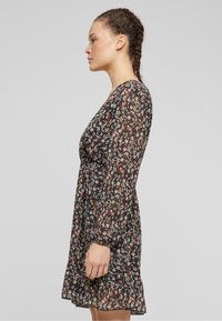 Black floral dress with long sleeves, frilled hem, sheer chiffon material, featuring multicolored floral patterns and a fitted waist.