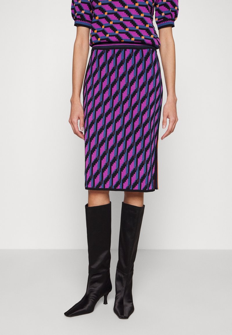 Gonna a matita lavorata a maglia con motivo a diamante viola, nero e blu. Abbinata a stivali neri in raso fino al ginocchio.