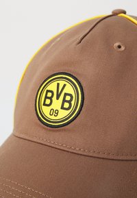 Brown cap featuring a rounded bill, yellow accent on the edge, and a circular black and yellow embroidered logo labeled "BVB 09."