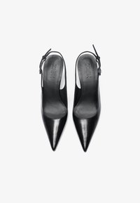 Juodos odinės slingback aukštakulniai batai su smailiais pirštais, lygiu paviršiumi, maža sagtimi ant kulkšnies dirželio ir prekės ženklu ant įdėklo.