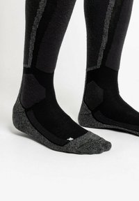 Schwarze und graue Socken mit einem strukturierten Muster, ausgestattet mit verstärktem Zehen- und Fersenbereich, elastischer Fußgewölbeunterstützung und einem gerippten Bund für besseren Sitz.