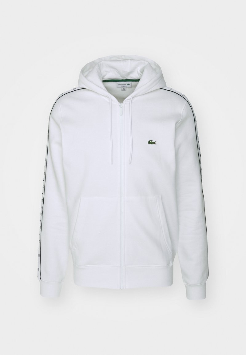 Felpa bianca con zip in misto cotone, dotata di una tasca frontale, un logo ricamato verde sul petto e strisce laterali a contrasto.