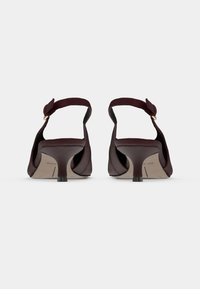 Ζευγάρι μωβ σκούρα γκρίζα σουέντ γόβες με λουράκια στον αστράγαλο και μικρά τετράγωνα τακούνια, φω�τογραφημένες από πίσω σε λευκό φόντο.