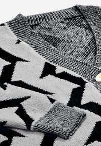 Maglione lavorato a maglia con scollo a V, motivo a zigzag nero e grigio, colletto a coste e un dettaglio con pulsante in contrasto sul collo.