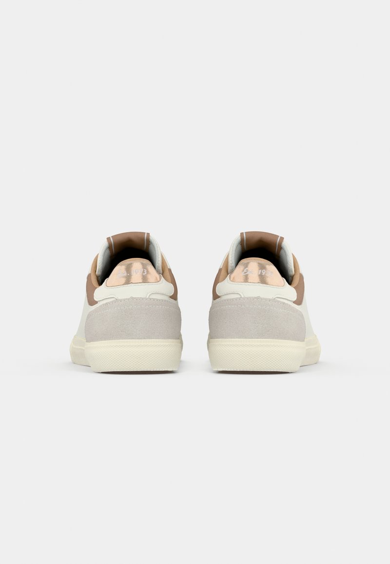 Zapatillas con una parte superior de cuero beige liso, acentos de gamuza gris claro y un tacón marrón. Presentan un cuello acolchado y suela de goma.
