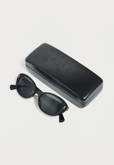 Μαύρα οβάλ γυαλιά ηλίου με σκούρους φακούς τοποθετημένα δίπλα σε μια μαύρη σκληρή θήκη με ανάγλυφο το λογότυπο "Ralph Ralph Lauren".