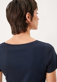 Marineblauwe shirt met korte mouwen, een brede, ronde halslijn en een zachte textuur. Heeft een eenvoudig, strak ontwerp zonder patronen.