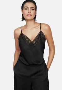 Zwarte satijnen cami met verstelbare spaghettibandjes, voorzien van een kanten V-halslijn en gedetailleerde kanten afwerking langs de randen.