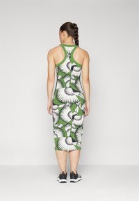 Vestido verde com padrão de pássaros, design justo, estilo de costas nadador, até ao joelho, com detalhes em preto e combinado com ténis pretos.