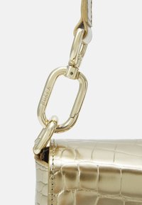 Sac en cuir doré effet crocodile avec une attache en chaîne métallique, possédant une texture lisse et une finition brillante.