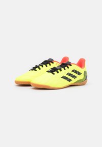 Bright yellow athletic shoes with black accents, a smooth texture, and rubber soles. Features laces and a padded orange collar at the heel.