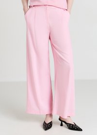 Pantalon à jambes larges en tissu rose doux à la texture lisse, doté de poches latérales et d'une ceinture ajustée.