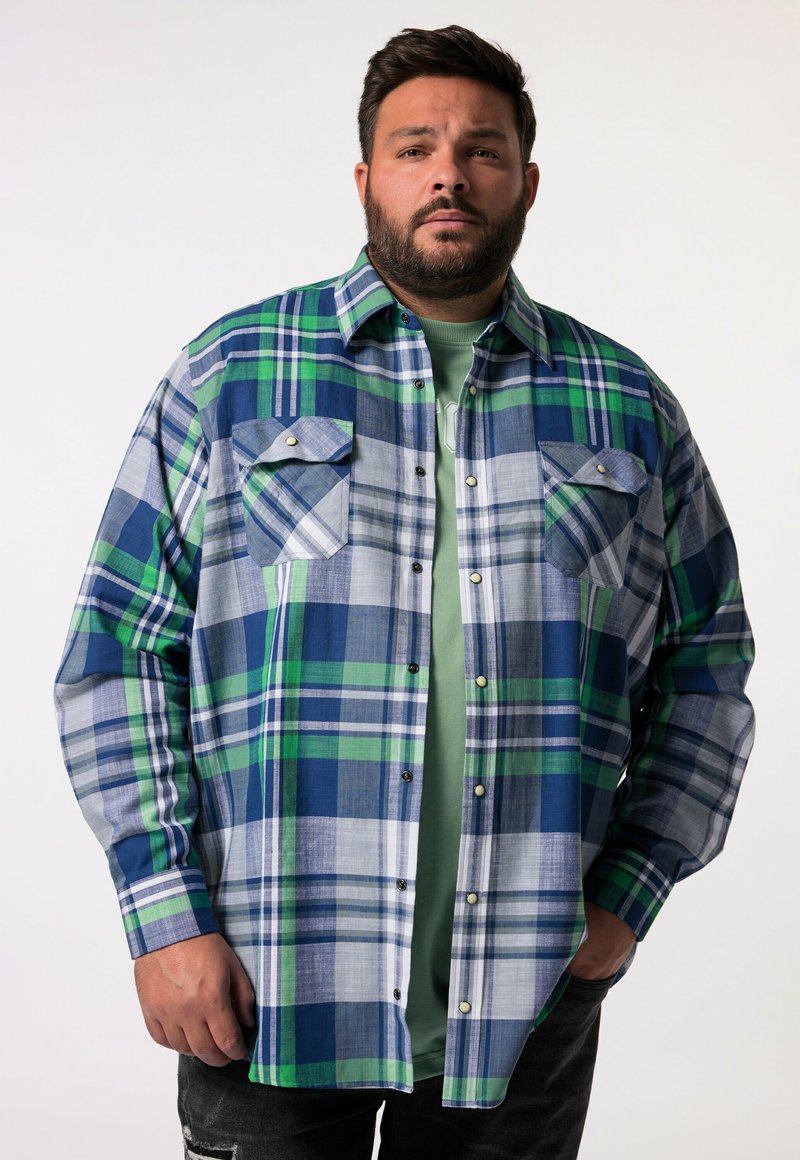 Camicia flanella a quadri blu e verde con due tasche sul petto, maniche lunghe e chiusura con bottoni. Presenta strisce bianche e blu navy in contrasto.