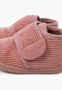 Scarpe slip-on in corduroy rosa con tessuto testurizzato, cuciture rinforzate e una strap Velcro. Fodera morbida e suola in gomma flessibile.