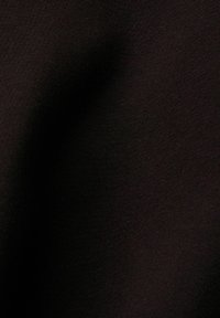 Tissu noir avec des plis subtils et une texture fine visible sous un éclairage doux.