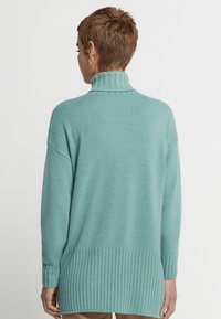 Långärmad, mintgrön tröja med ribbad hög hals och nederkant. Mjuk textur och avkopplad passform som sträcker sig förbi höfterna.