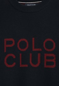 Marineblauer Strickpullover mit dem kühnen roten Schriftzug "POLO CLUB" auf der Vorderseite. Gerippter Rundhalsausschnitt und strukturierter Stoff.