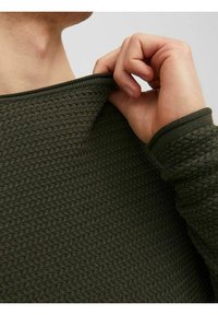 Zielony dziergany sweter o fakturowanym wzorze, z okrągłym dekoltem i ściągaczowymi mankietami. Tkanina wydaje się miękka i elastyczna.